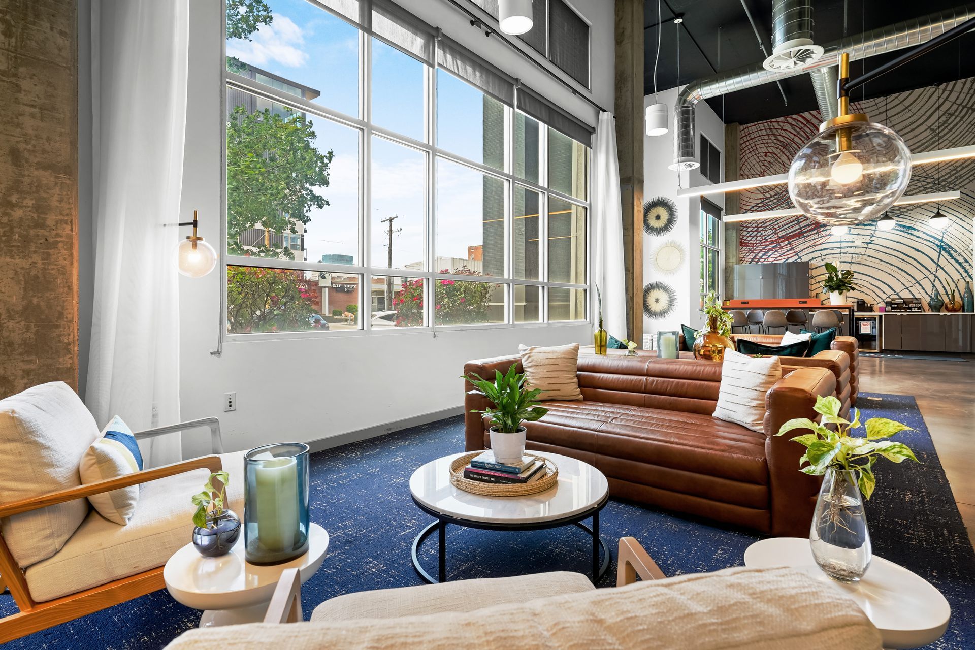 Cozy lounge room with leather sofa, blue rug, large window, and city view.