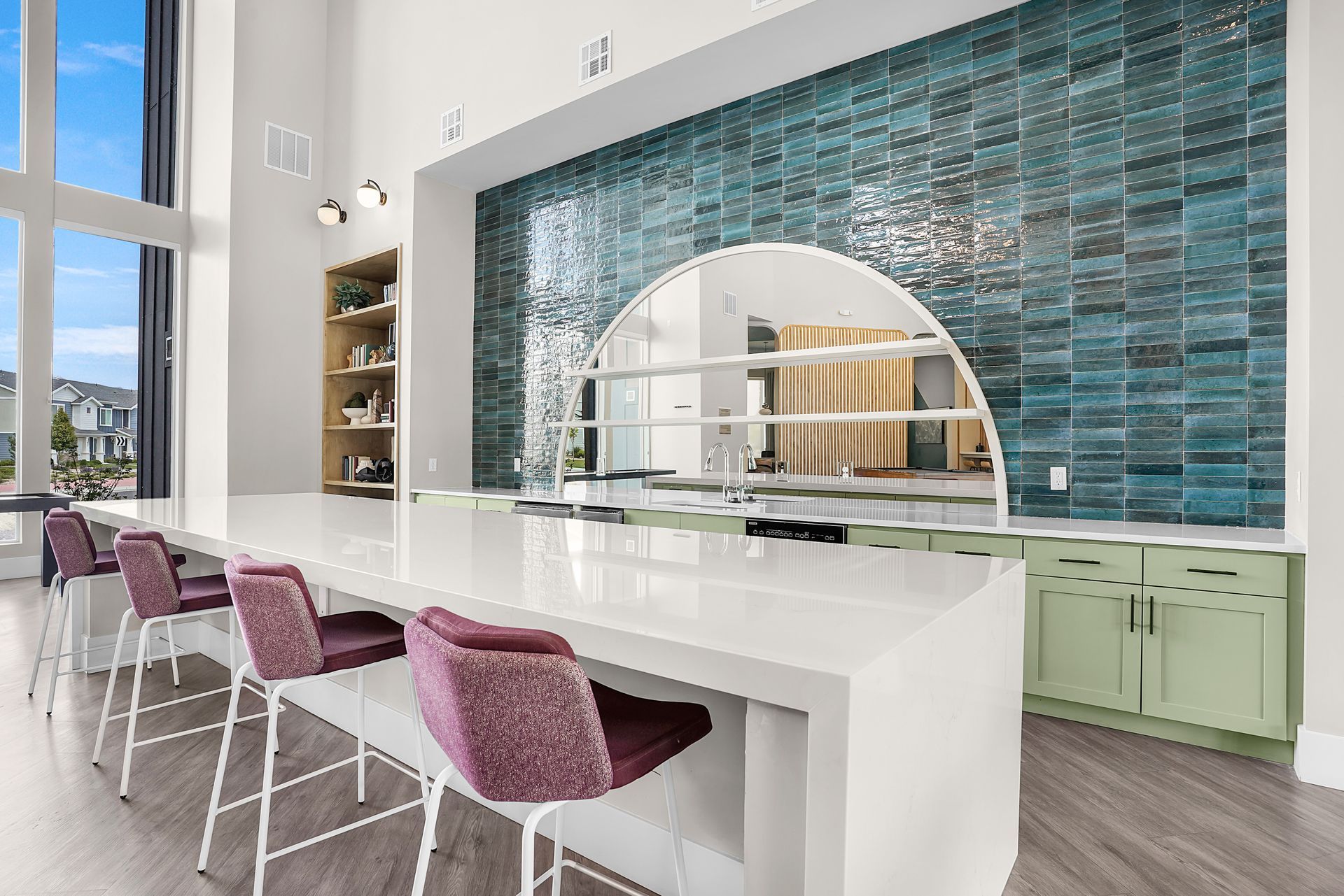Modern kitchen with a long white island, teal tile wall, and purple bar stools.