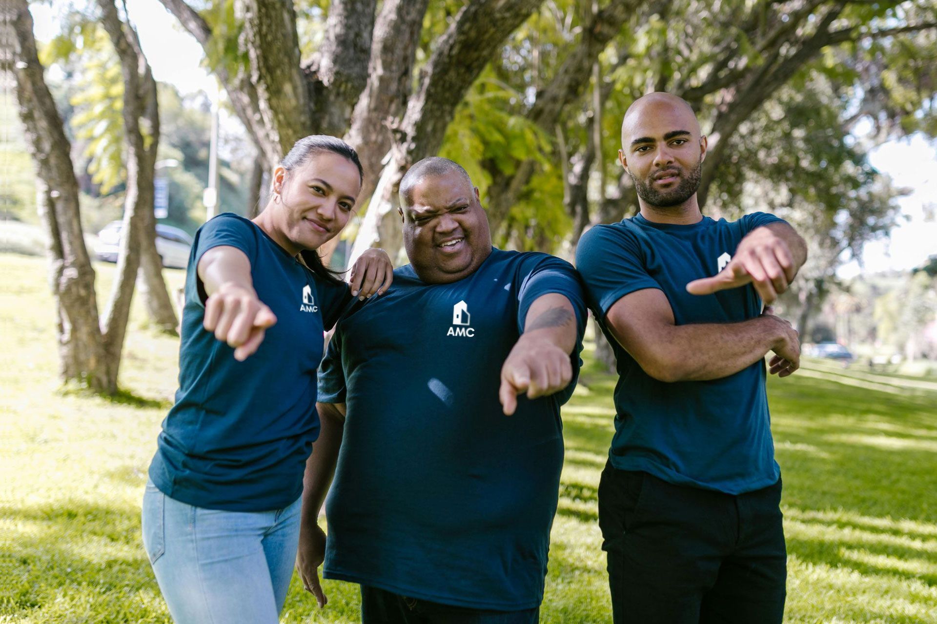 Overhead view of diverse group around a wooden table, two people shaking hands. Laptops and tablets are scattered.