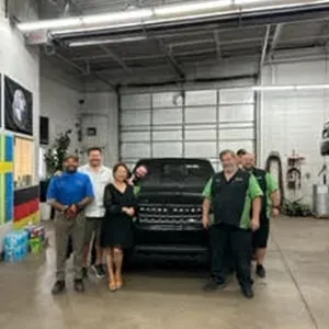 Staff around black car in garage | AutoImports of Denver