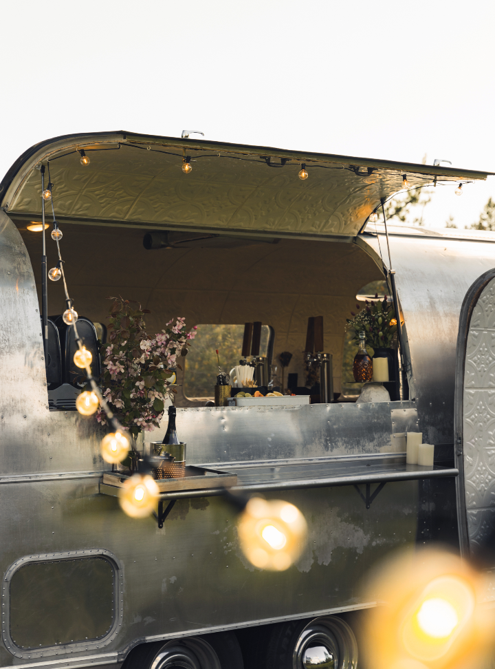 A silver trailer with the door open and a string of lights hanging from it.