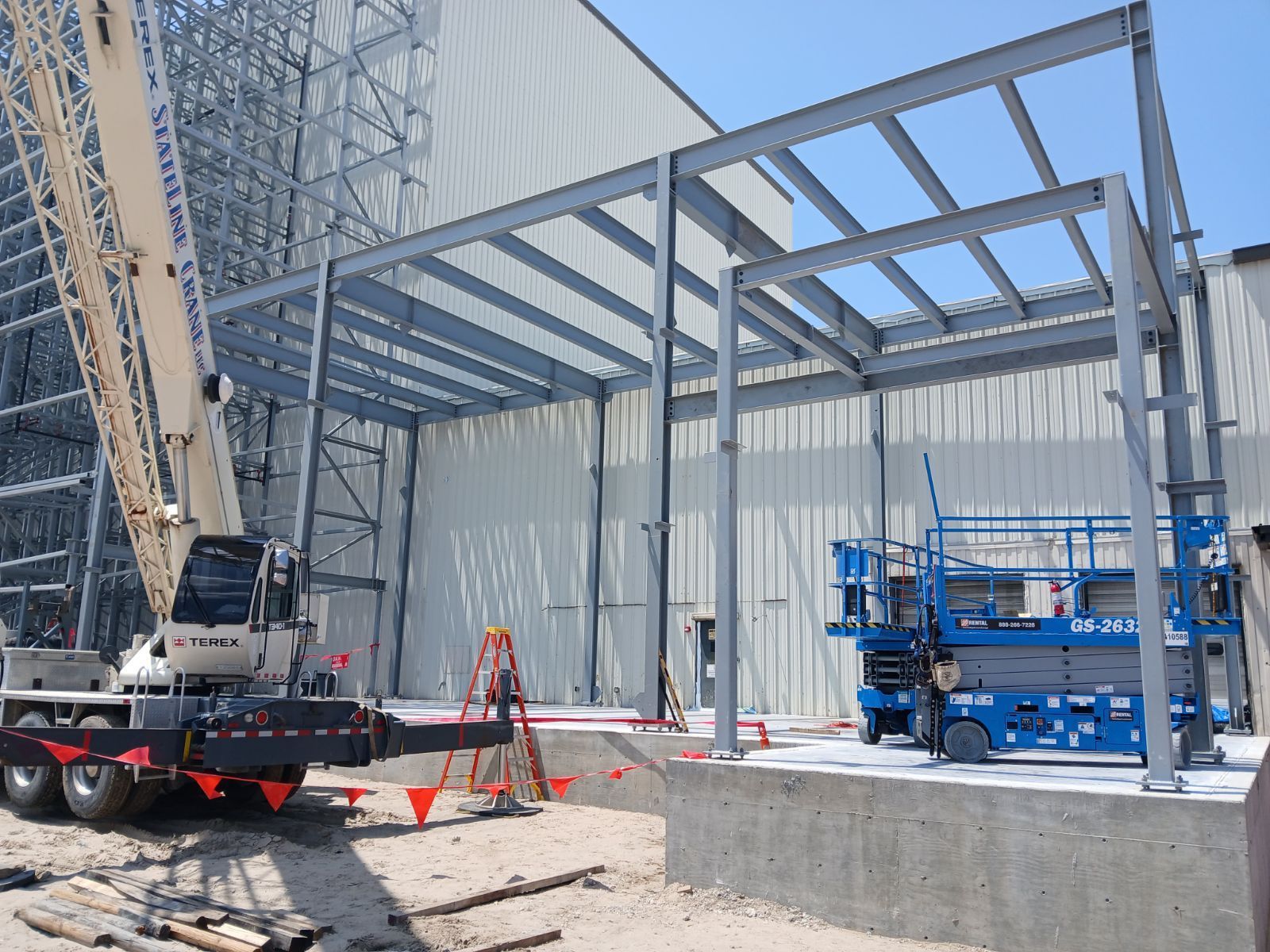 A crane is sitting in front of a building under construction.