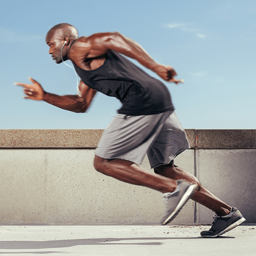 A man in a black tank top and grey shorts is running
