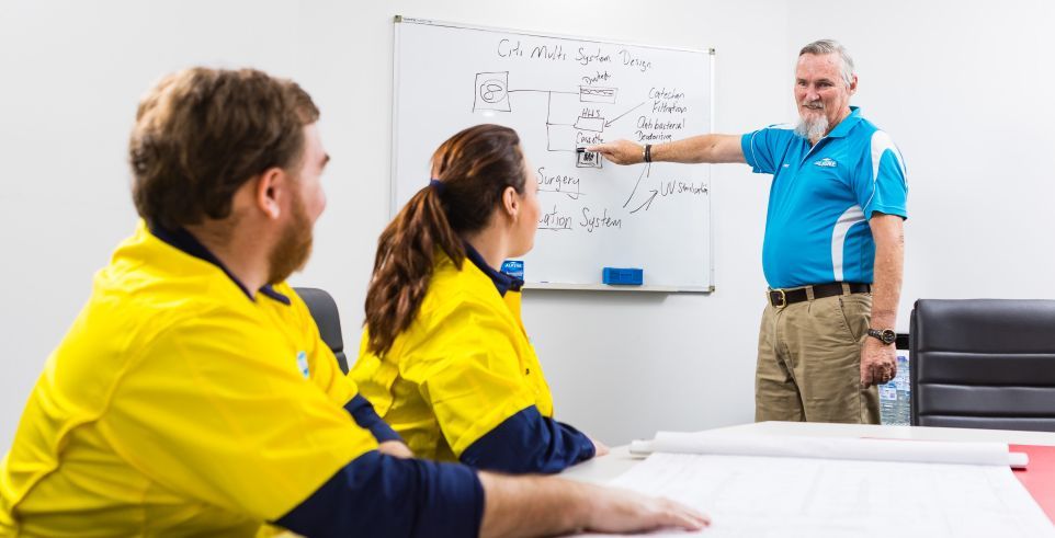 A man is giving a presentation to a group of people while sitting at a table.