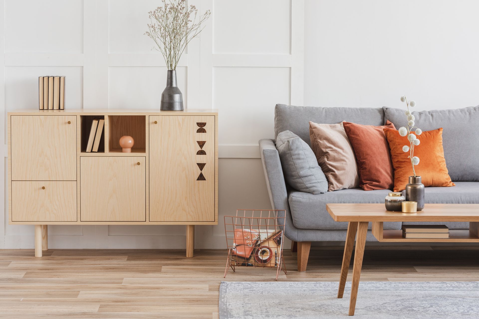 Living room with gray couch, wooden cabinet, coffee table, and floral decor.