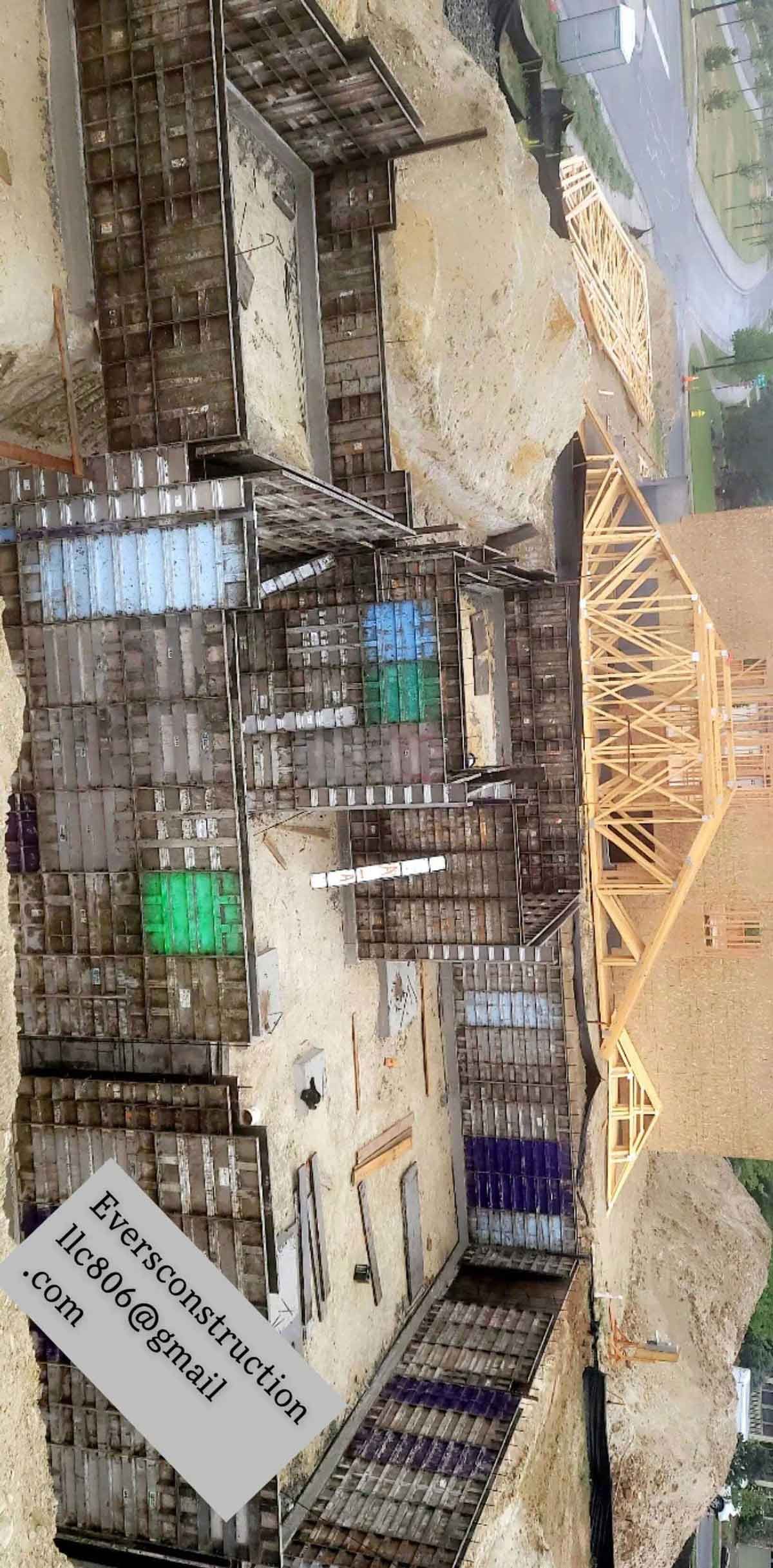 Overhead view of an old building with a bridge to the right. Various colored containers are visible.