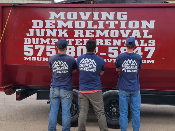 three men standing in front of a 20 yard dumpster