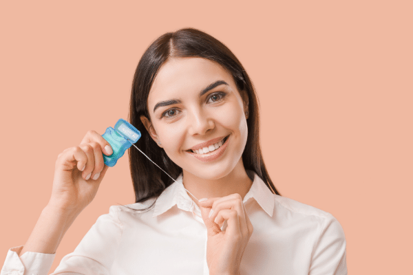 A woman is smiling while holding a credit card and floss.