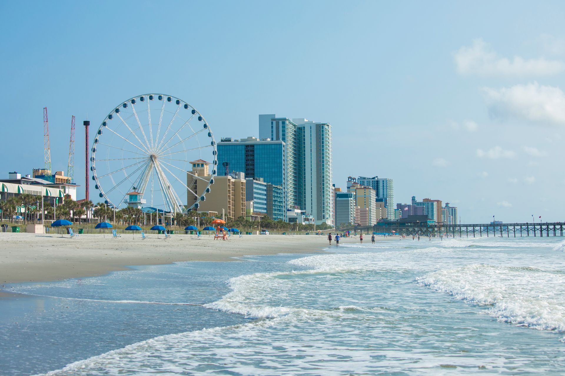 A beach with a ferris wheel in the background.