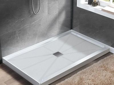 A white rectangular shower base with a centered square drain, installed against gray tiled walls in a bathroom.