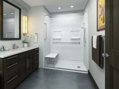 A modern, accessible bathroom with a dark wood vanity, light gray walls, and a walk-in shower featuring grab bars and a seat.