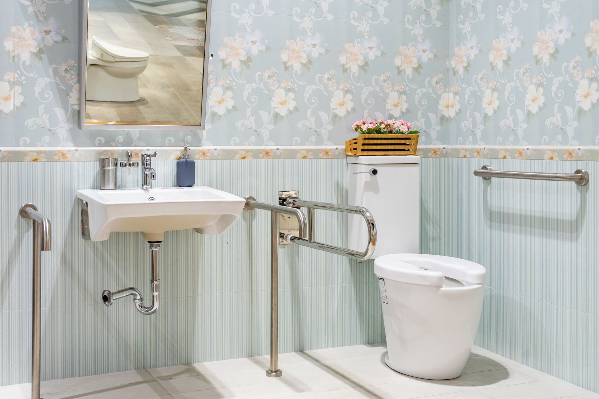 Accessible bathroom with sink, toilet, grab bars, and blue floral wallpaper