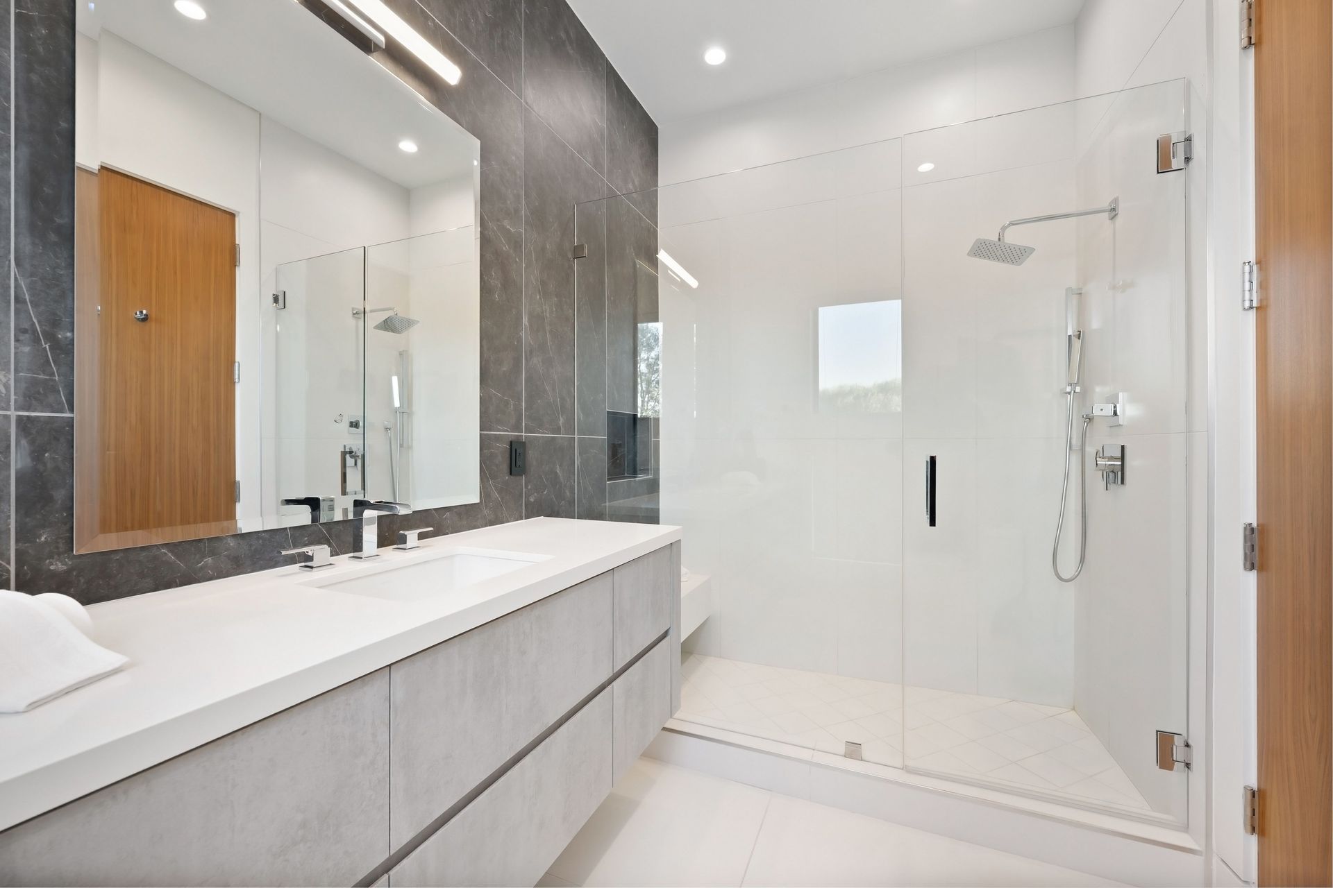 Modern white bathroom with double vanity, large mirror, and glass walk-in shower
