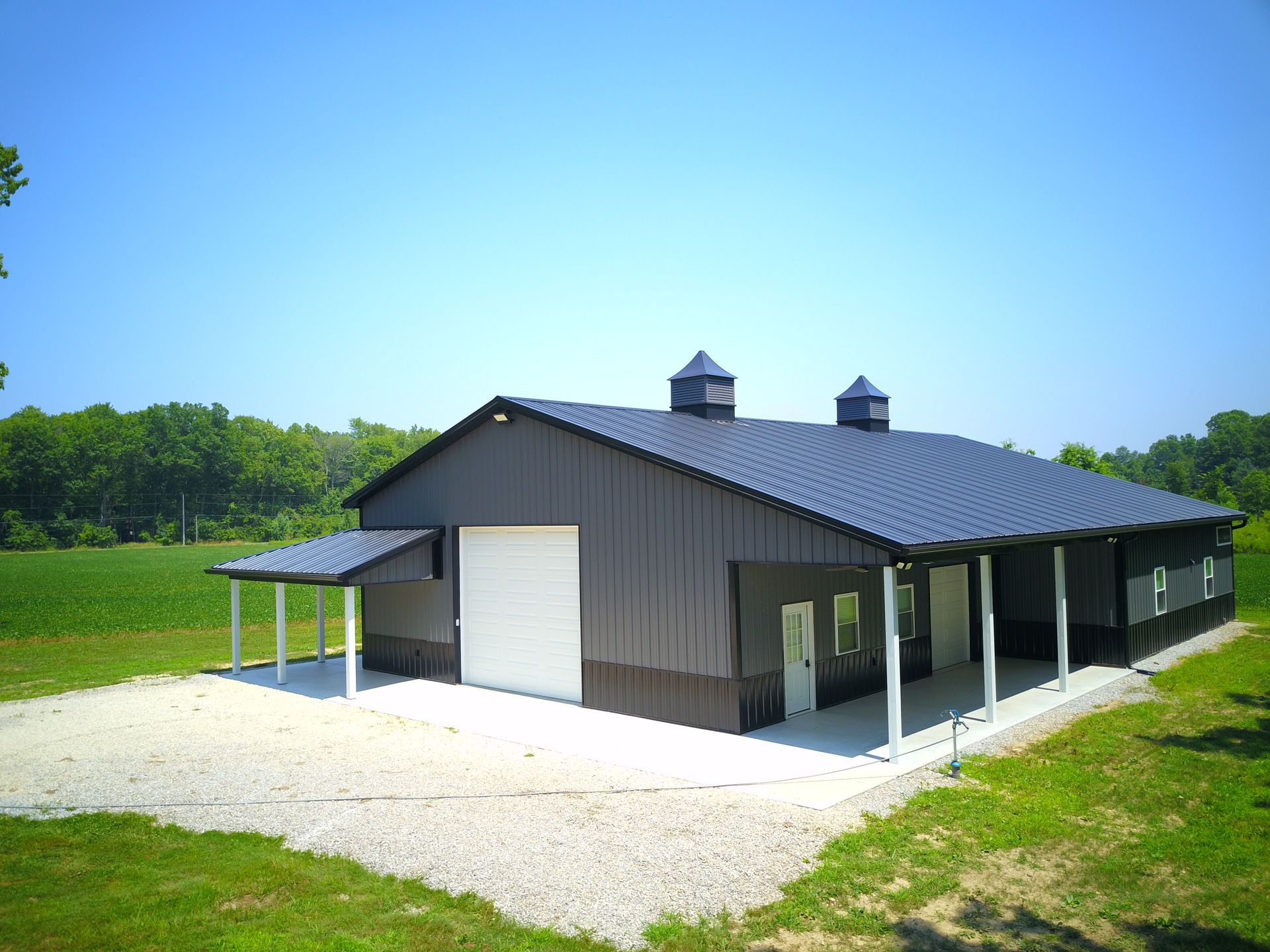 Black and brown barn with a white garage door and covered porch.