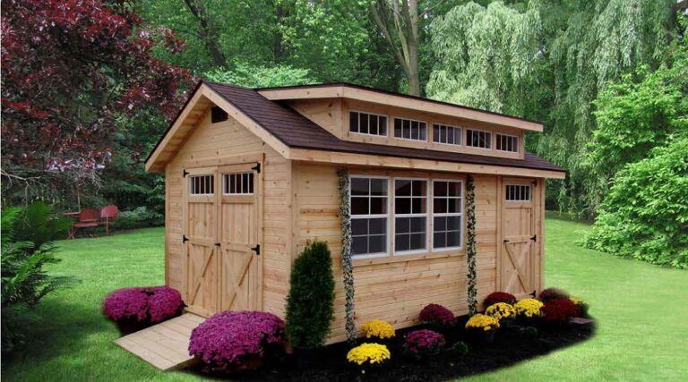 Wooden shed with gable roof, double doors, and windows, set in a backyard with grass, flowers, and trees.