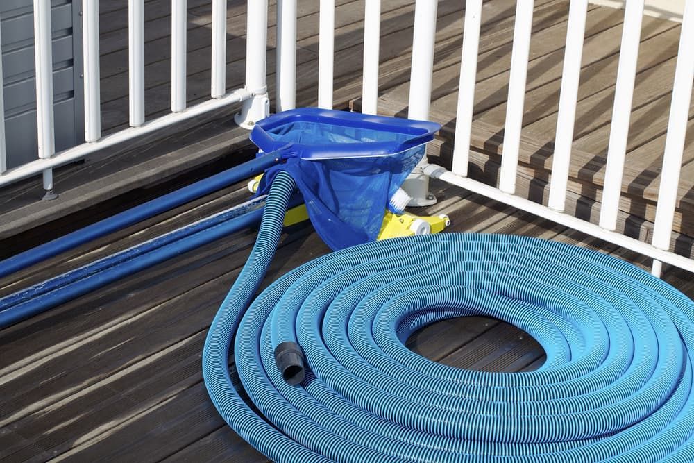 A Blue Hose is Sitting on a Wooden Deck Next to a Fence — Intouch Pools & Spas in Forster, NSW