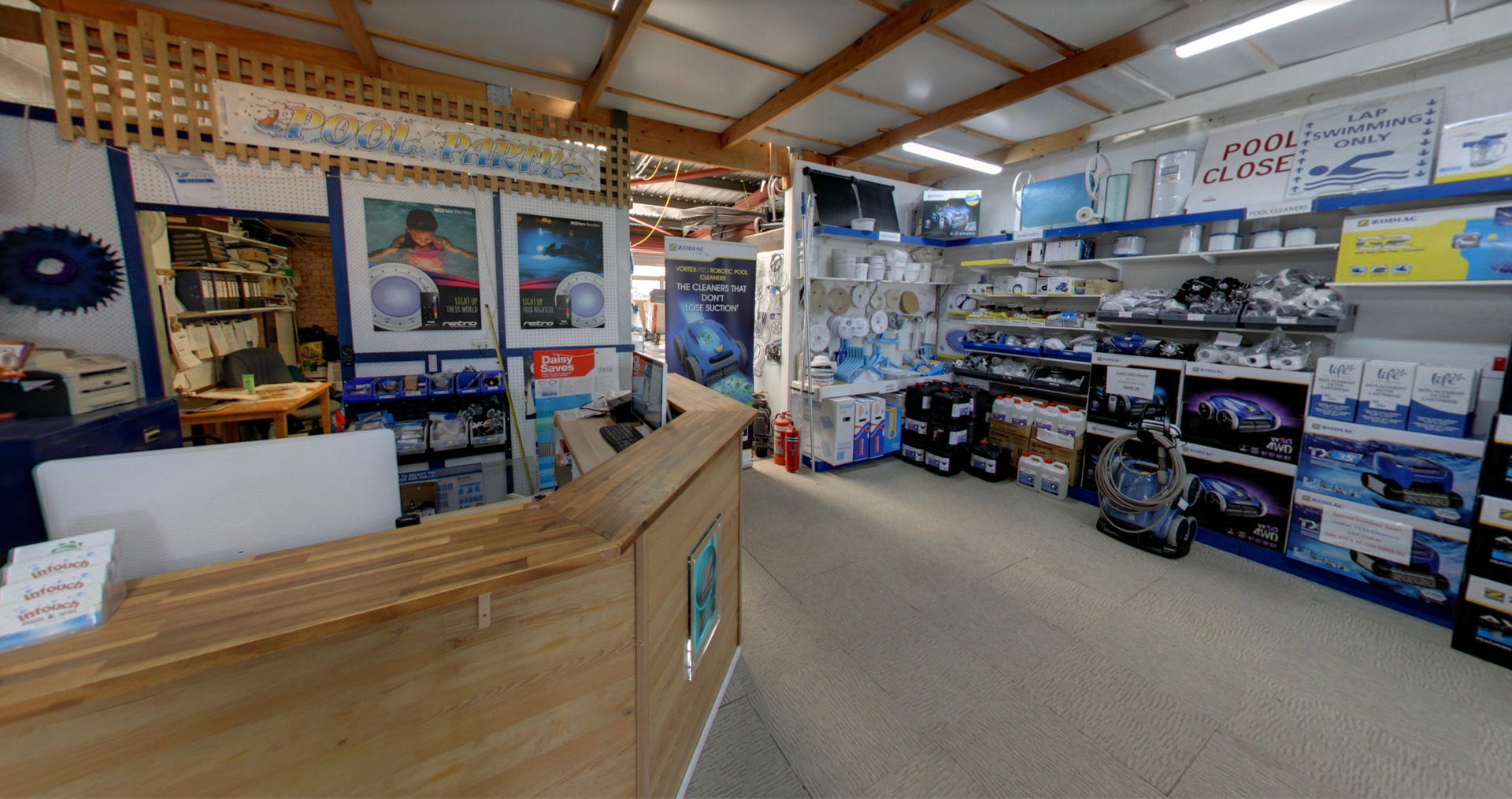 Inside a shop with a wooden counter. Shelves display various blue and white products. — Intouch Pools & Spas in Forster, NSW