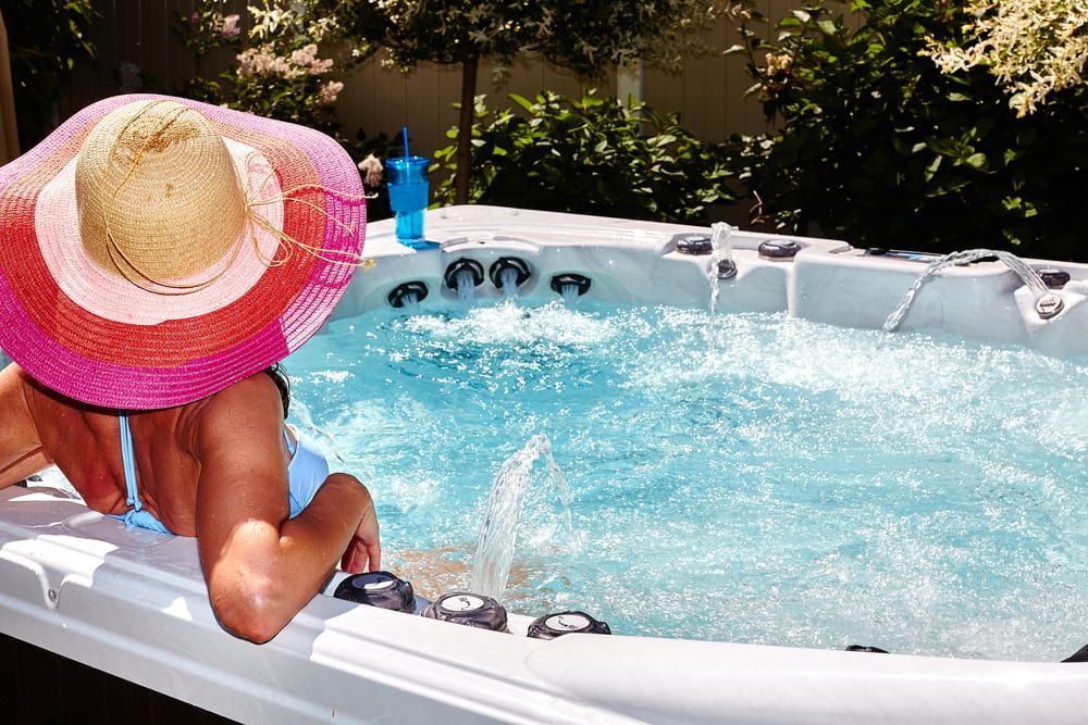 Woman in a Large Sun Hat Relaxing in a Hot Tub Outdoors — Intouch Pools & Spas in Taree, NSW
