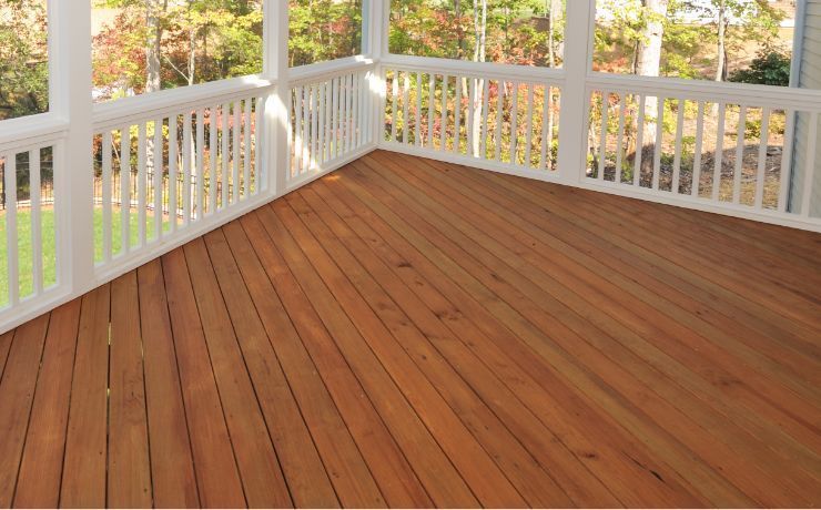 A wooden porch enclosed with white railings, showing richly stained decking boards, in the serene outdoors of Tempe, Arizona.