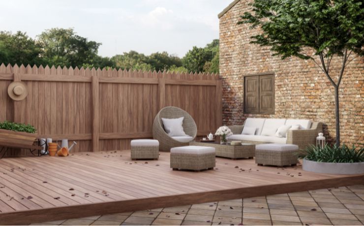 Inviting wooden deck with comfortable outdoor lounge furniture, encircled by a high privacy fence and vibrant greenery, in a Tempe backyard.