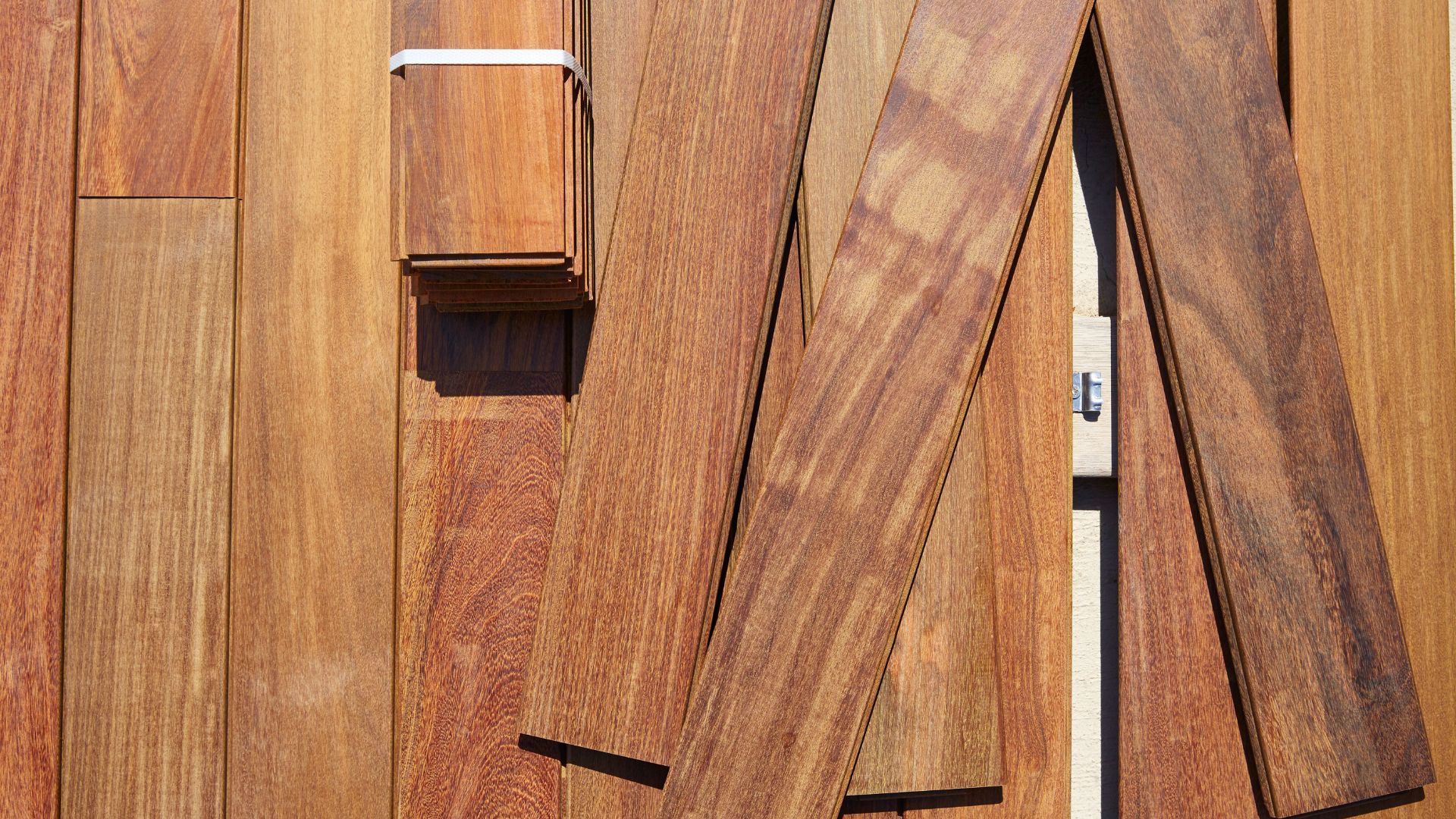 Stacked wooden deck boards in warm brown tones, showing textures and grains.