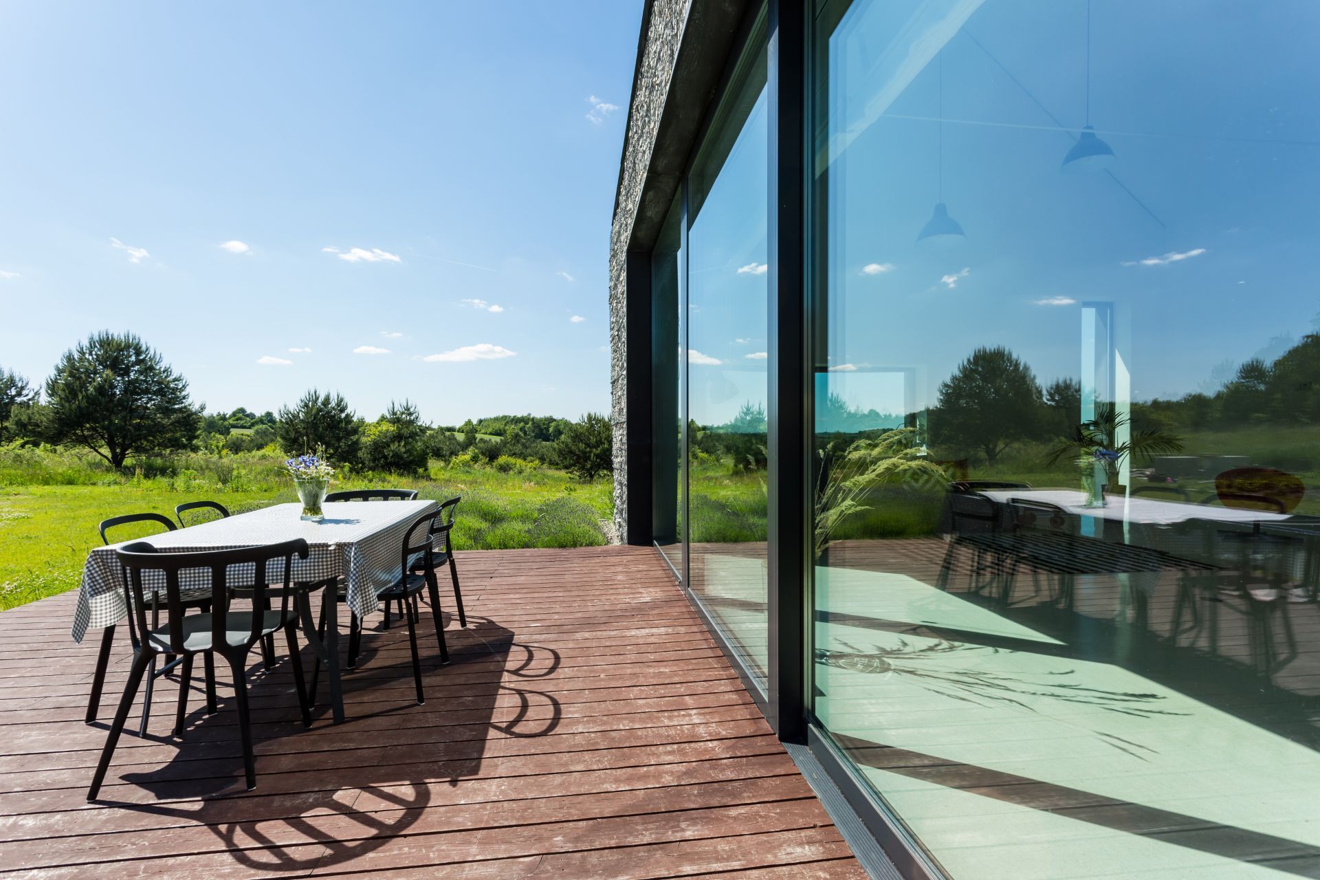 Modern deck with dining set overlooking a green landscape.