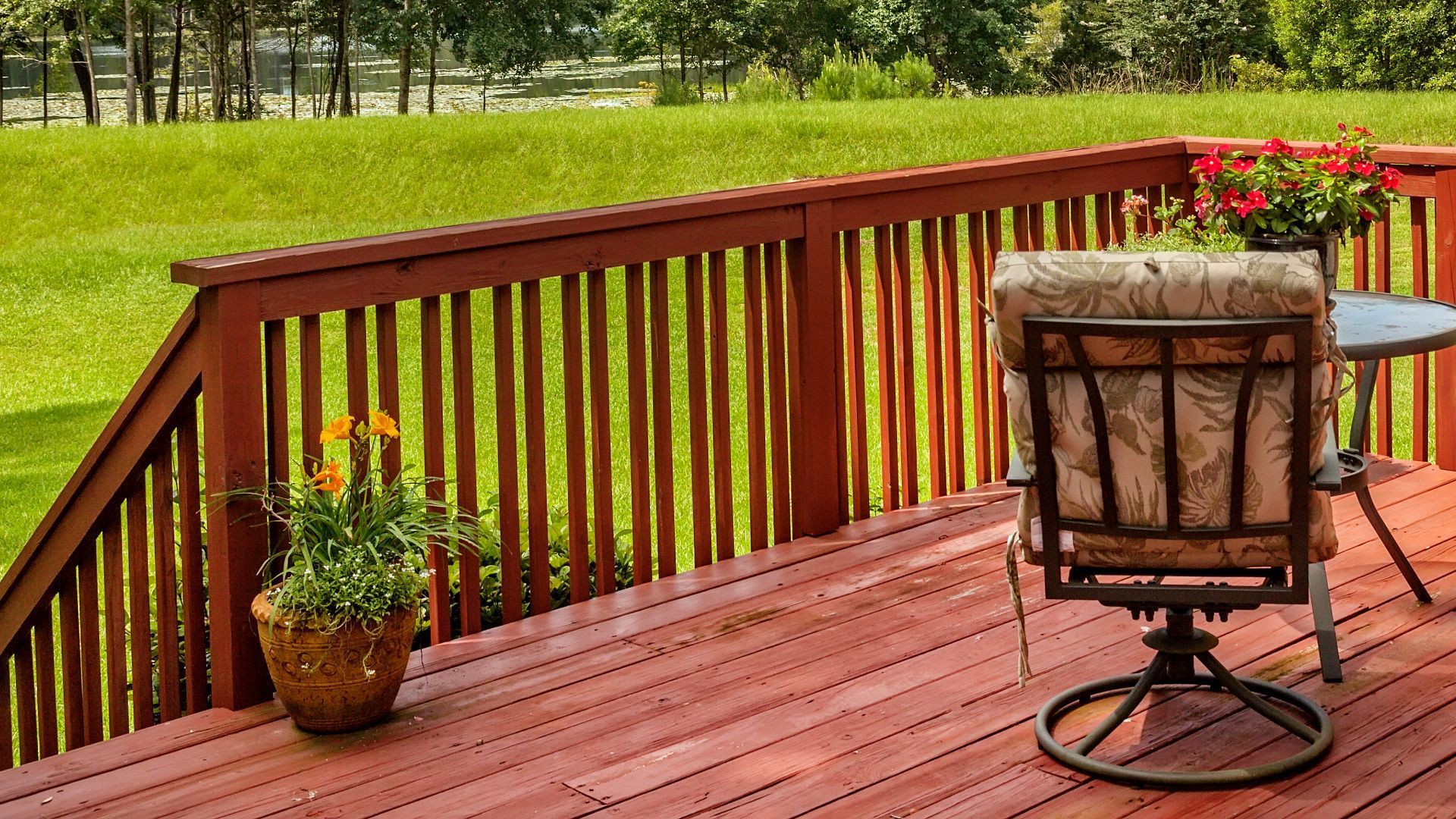 Red-stained deck with floral chair and lush greenery in Tempe, AZ, showcasing serene outdoor living.