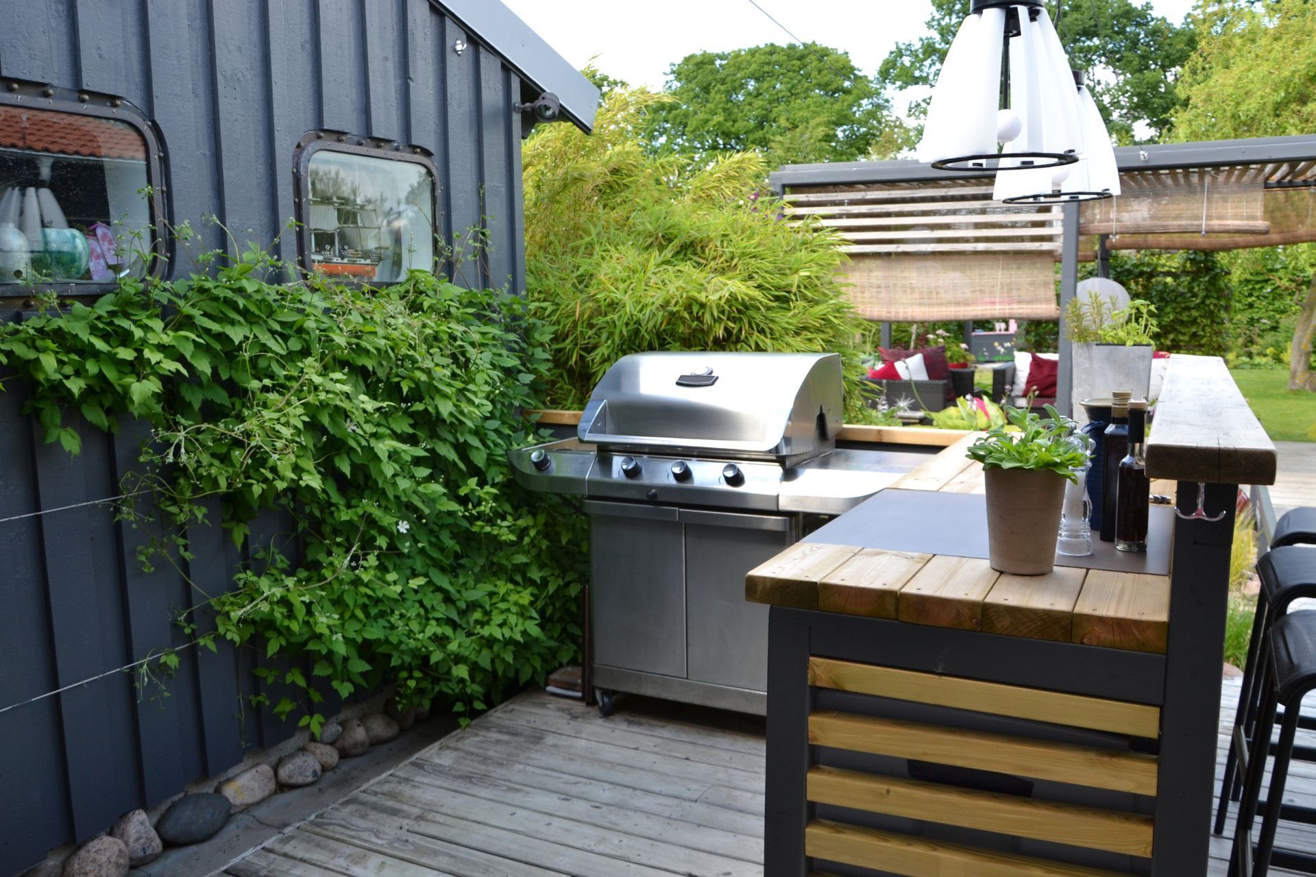 Outdoor kitchen with grill and wooden bar setup amidst greenery on a Tempe, AZ, deck.