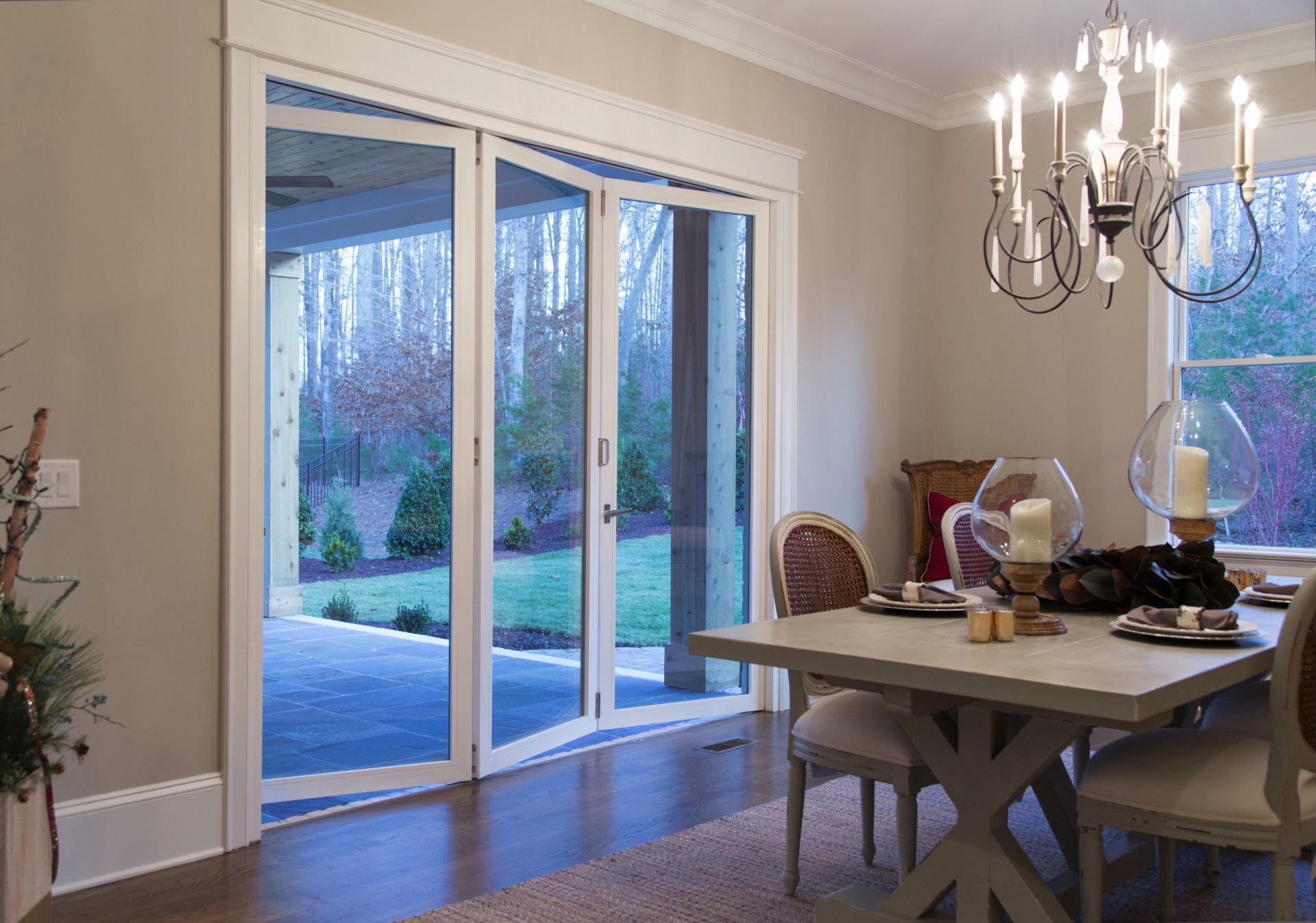 Dining room with glass doors opening to a patio and yard; table set for a meal.
