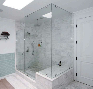 A luxurious bathroom with a large glass shower, marble walls, and a white door.