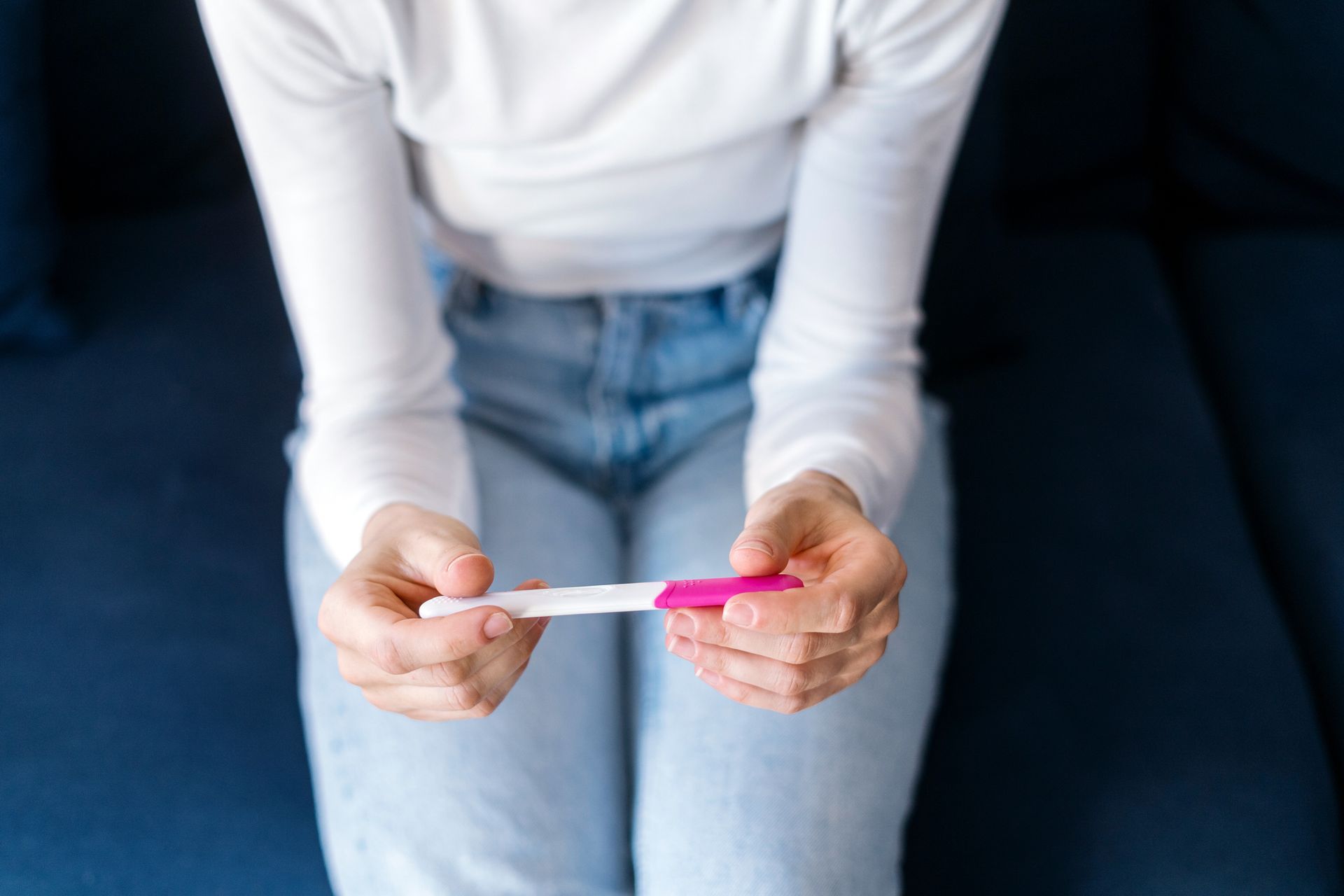Person holding a pregnancy test while sitting on a couch.