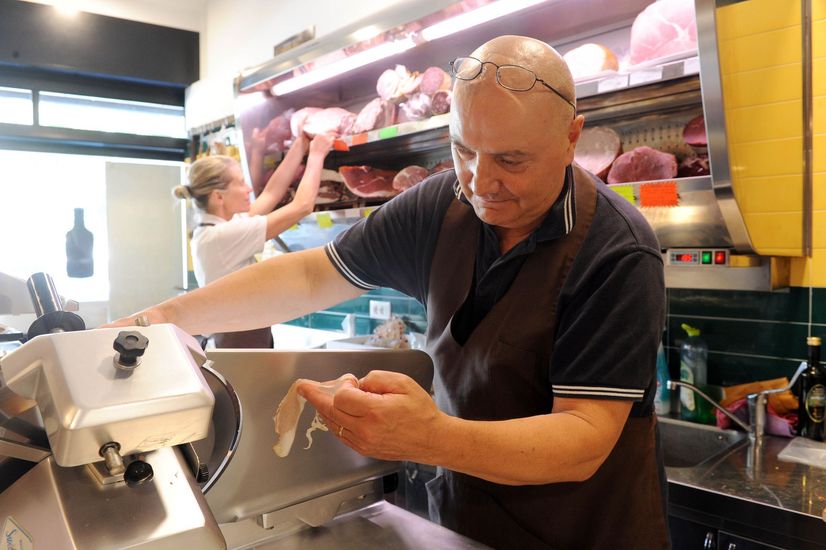 Una vetrina da banco gastronomia piena di insalate pronte assortite, quiche e snack, con barattoli di cibo sullo scaffale sopra.