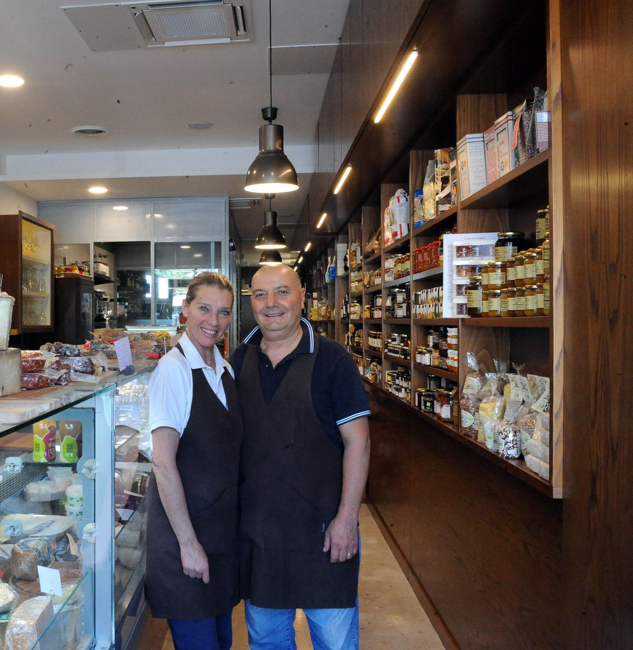 Decorazione a forma di cuore appesa davanti a un bar con bottiglie di vino, torte e altri oggetti esposti.