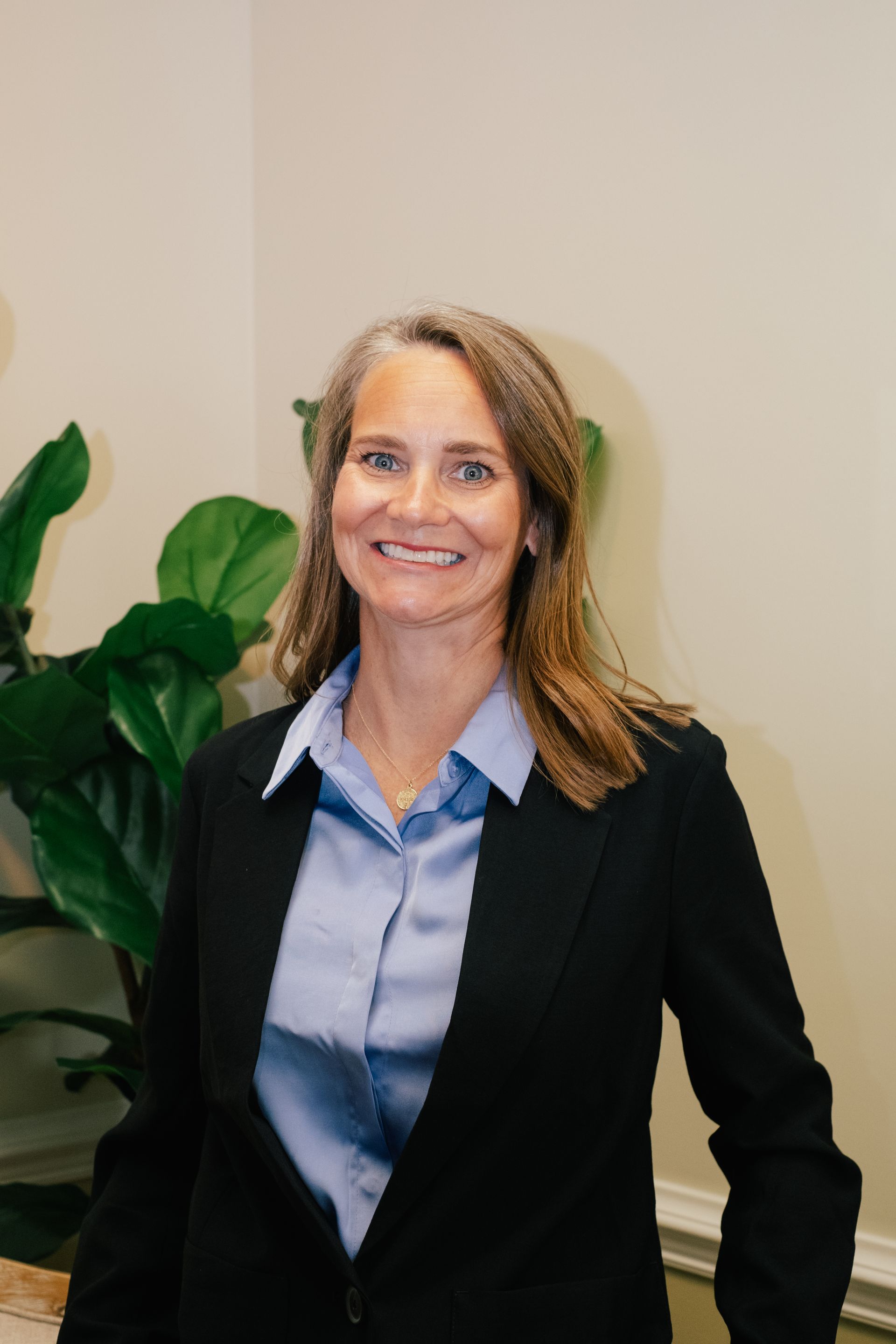 A woman in a blue jacket and white shirt is smiling for the camera