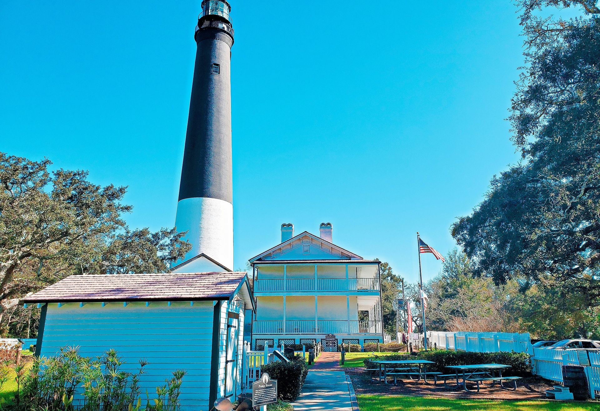 A lighthouse is sitting in front of a house.