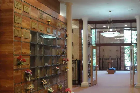 Indoor hallway with brick wall, glass display shelves, and a view into a bright atrium
