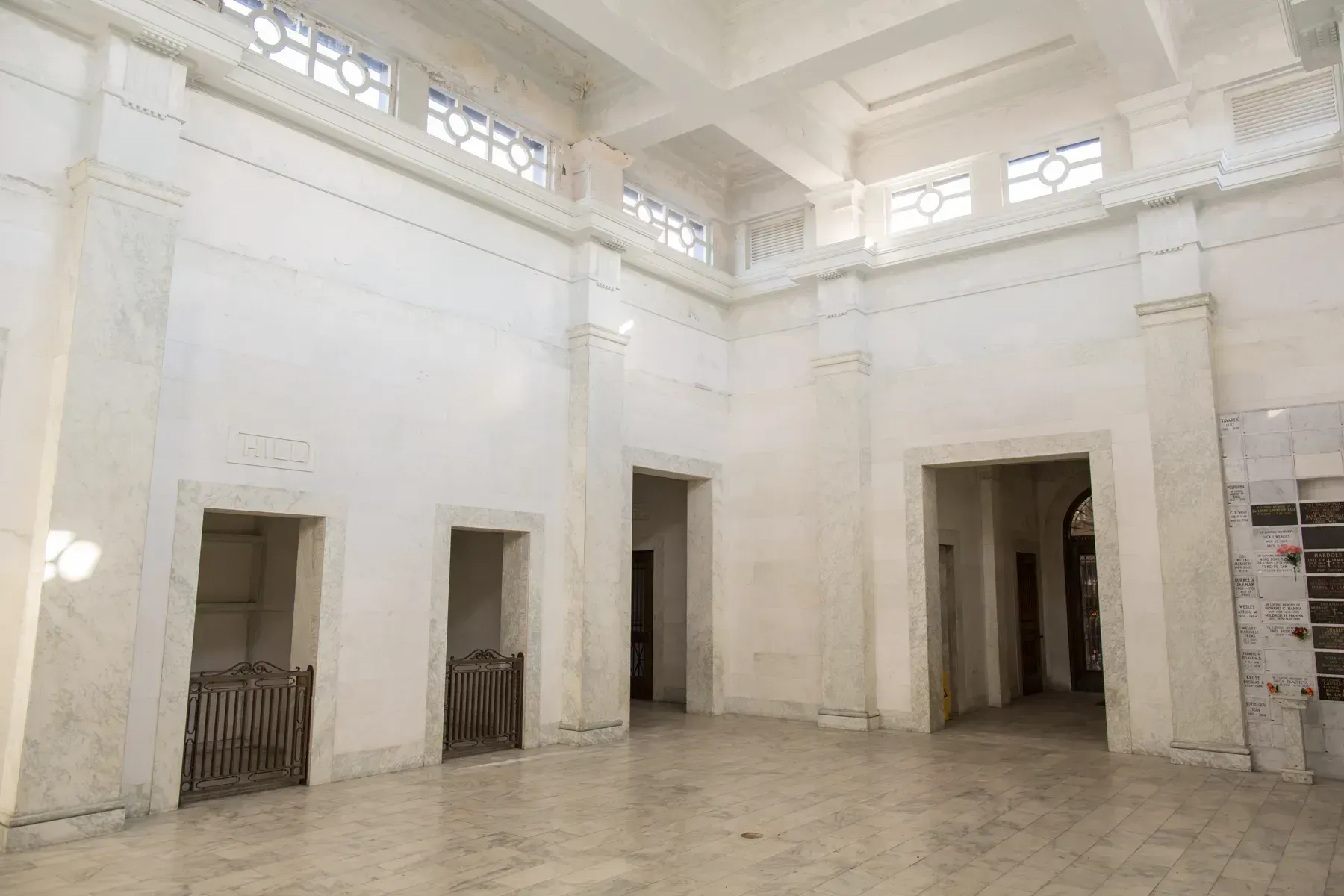 Bright white interior hall with high ceiling, doorways, and tiled floor