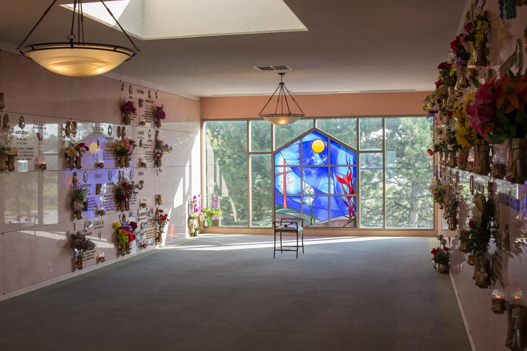 Flower-filled room with a blue stained-glass window and a chair on a carpeted floor