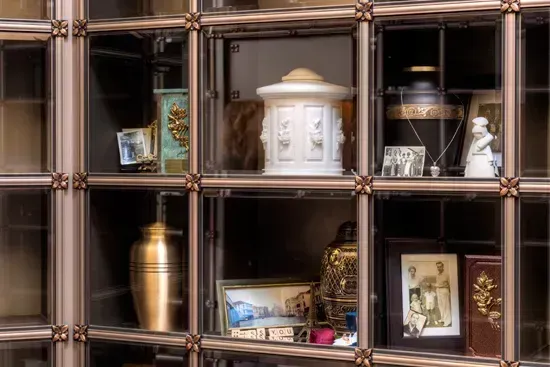 Decorative display of urns, framed photos, and keepsakes in a wooden cubby shelf