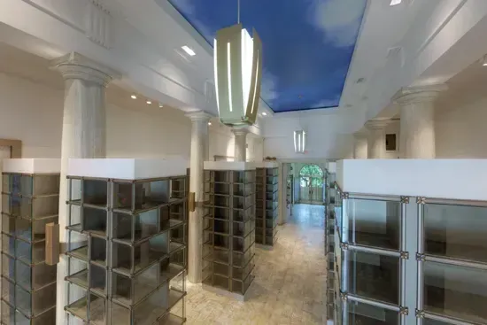 Bright hallway with tall shelving units and glass cabinets under a skylight ceiling