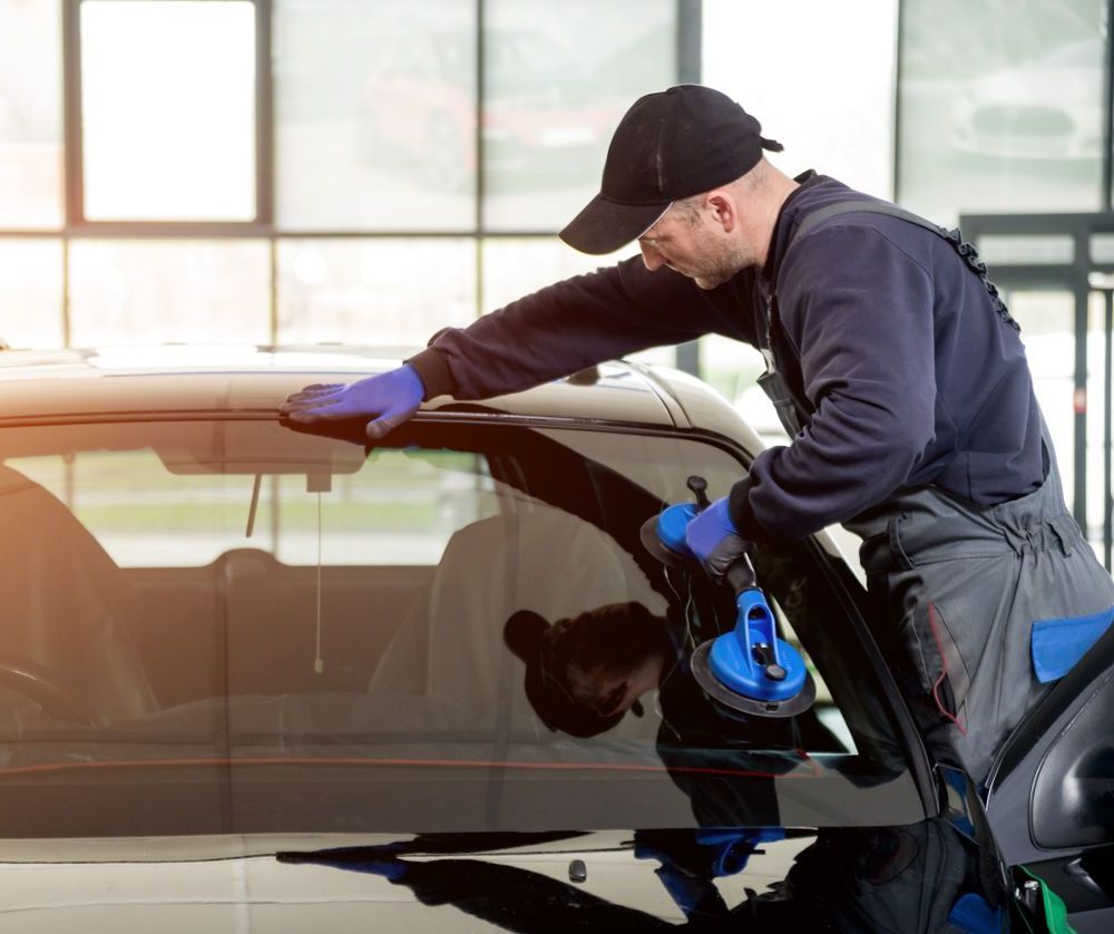 A Man Is Installing A Windshield On A Car — Petrena Windscreens In Millmerran, QLD