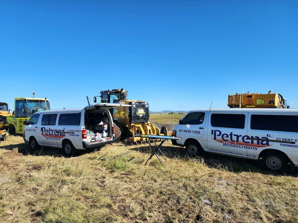 Two Vans Are Parked In A Field Next To A Tractor — Petrena Windscreens In Highfields, QLD