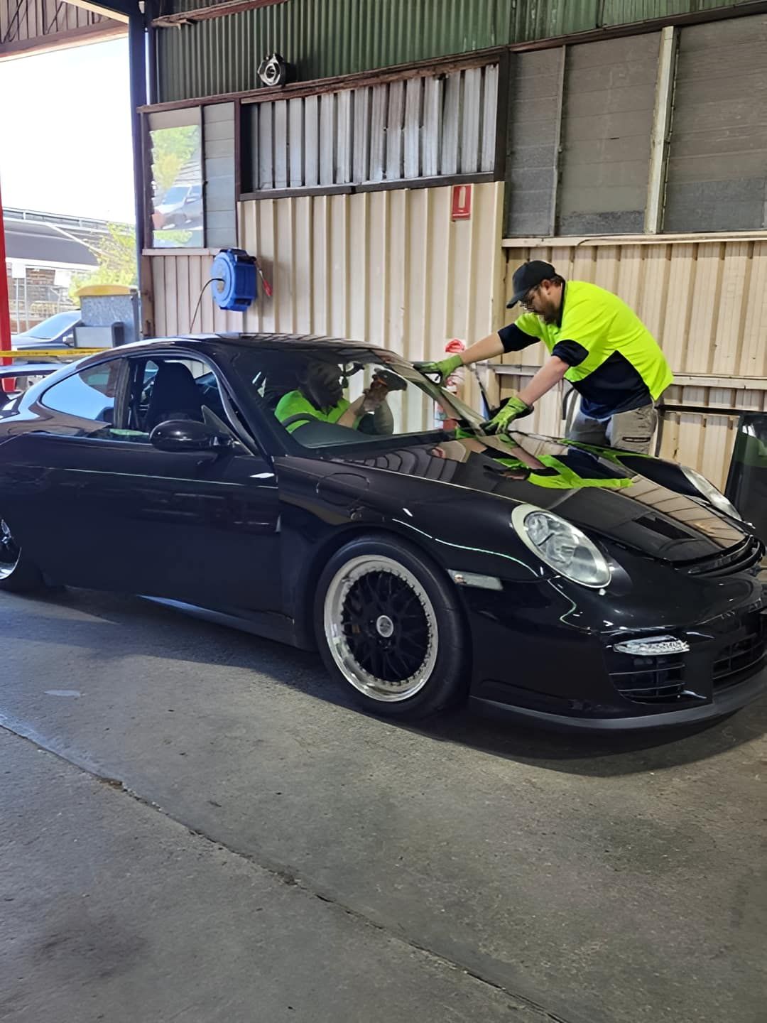 Two Men Are Working On A Black Sports Car In A Garage — Petrena Windscreens In Toowoomba City, QLD