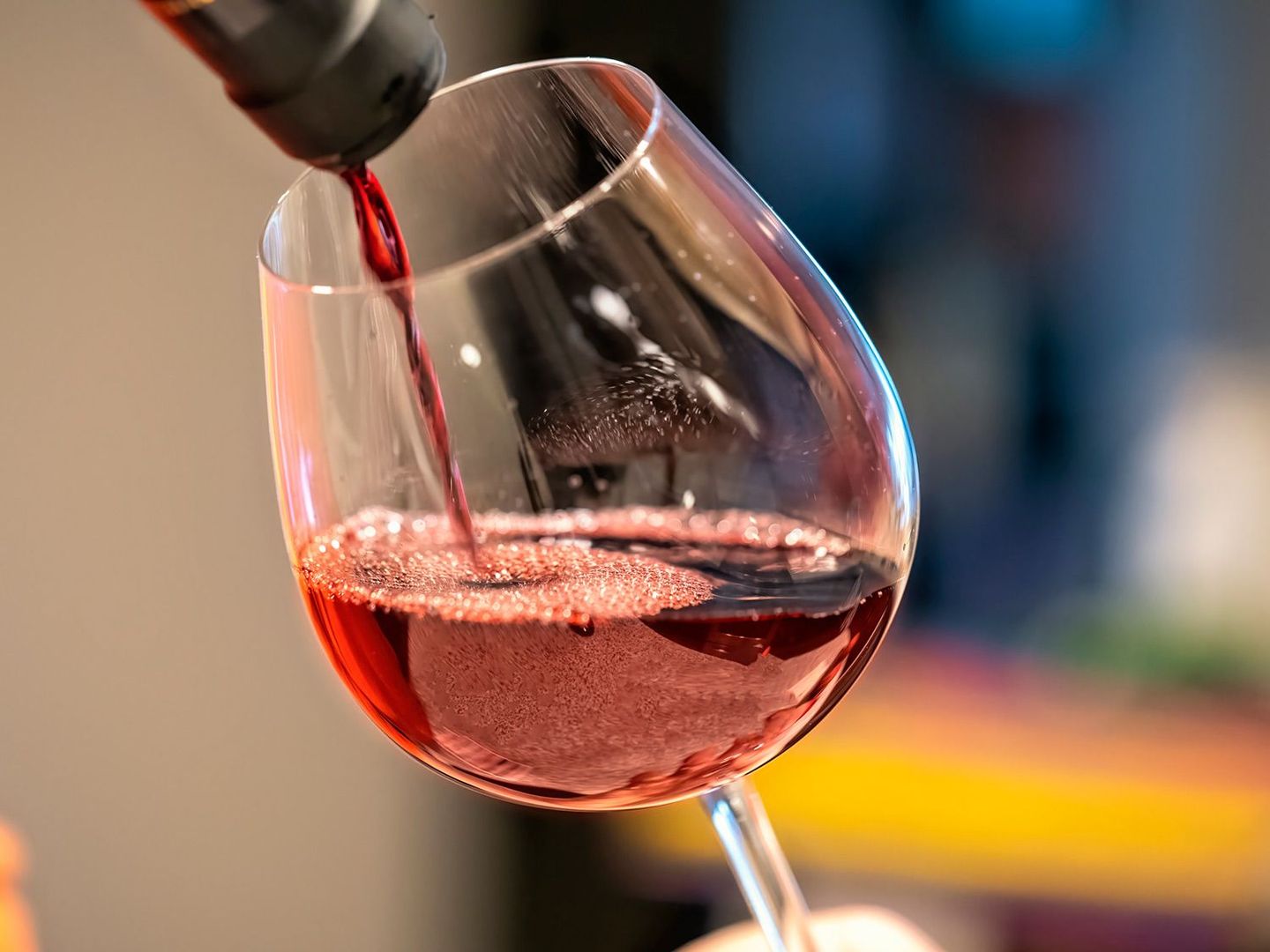 A glass of red wine is being poured from a bottle.