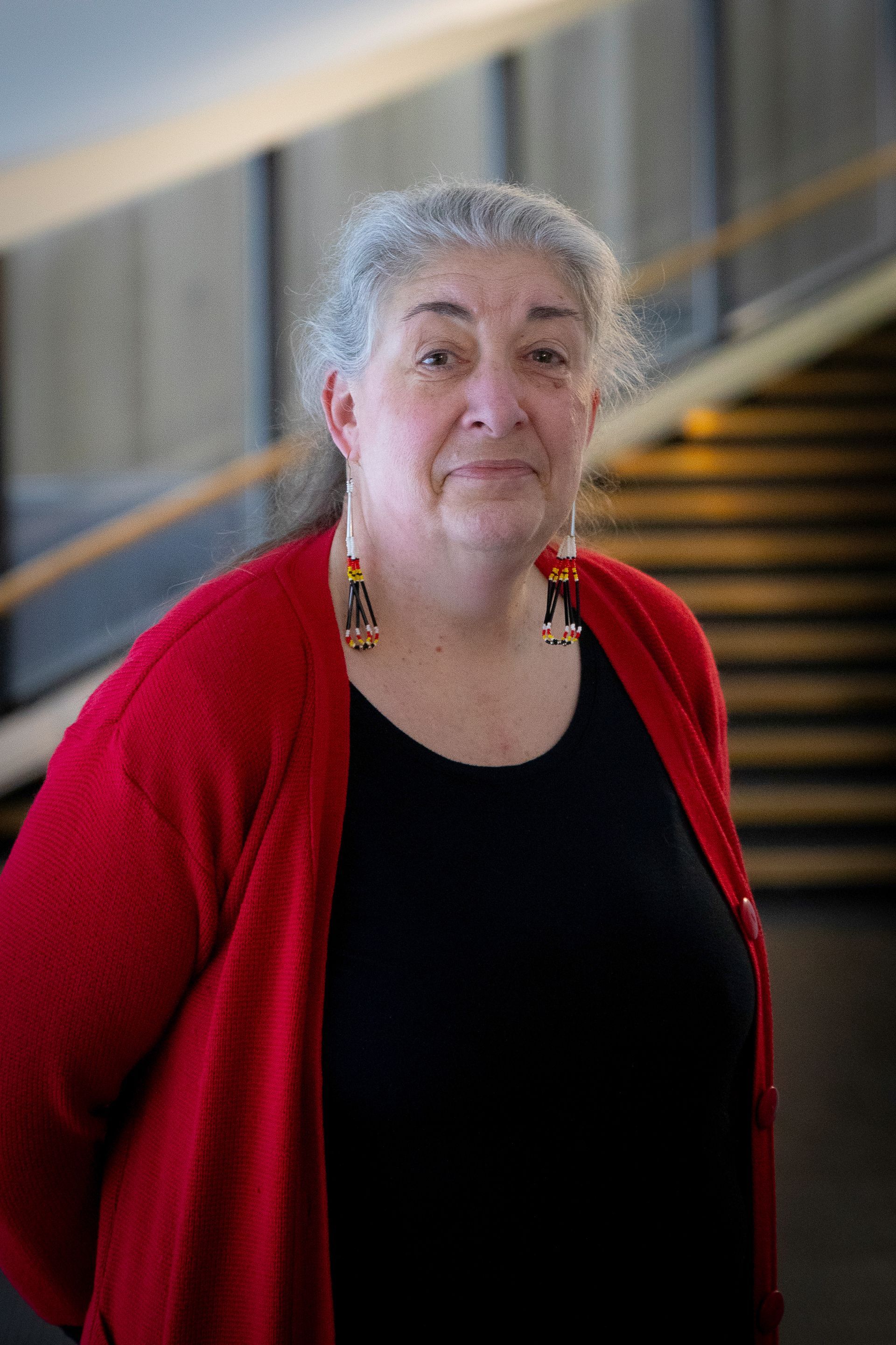Woman standing in front of stairs, smiling.