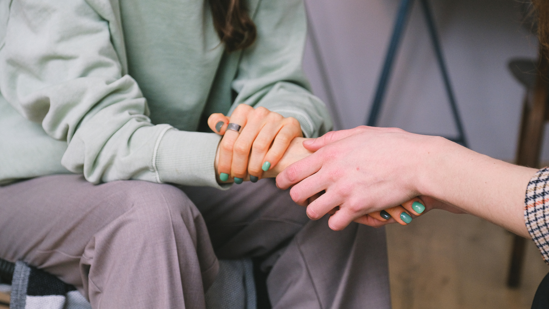 A woman is holding another woman 's hand while sitting in a chair.