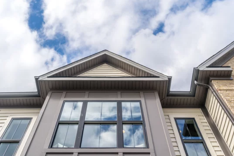 An overcast sky reflecting on a recently installed window, framed by sleek aluminum fascia.