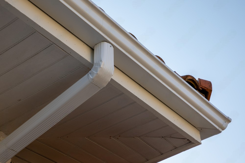 A close up of a white gutter on the roof of a house.