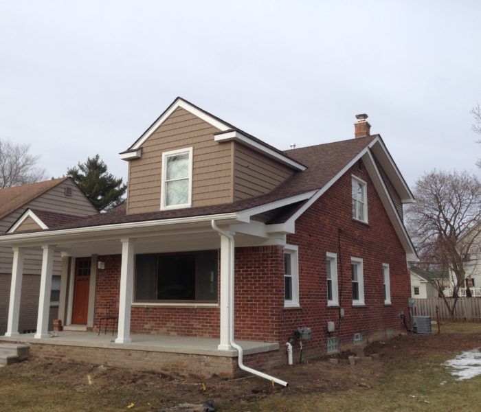 A brick house with a brown roof and a porch