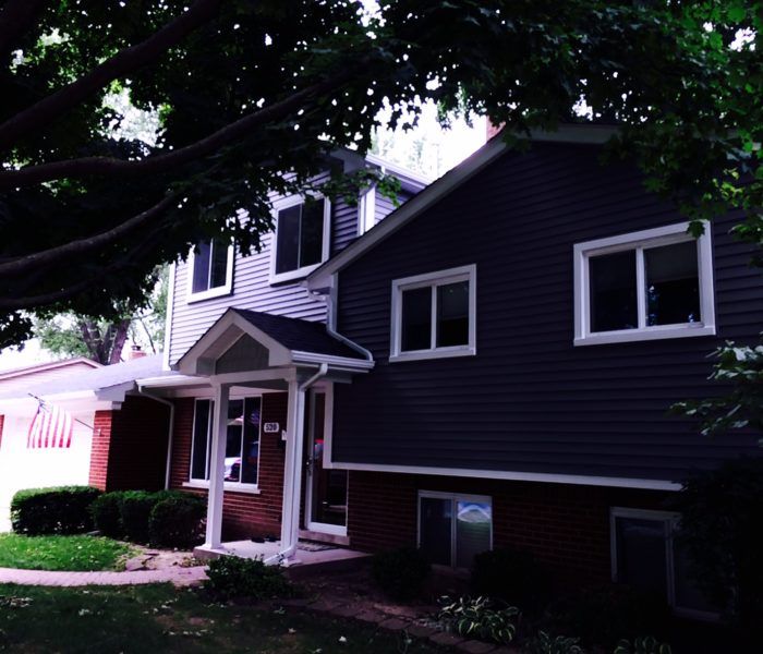 A house with a porch and a tree in front of it
